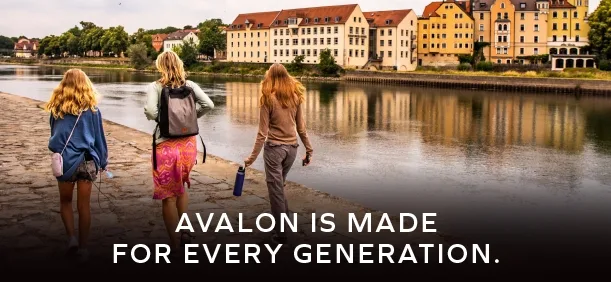 3 women of various ages walking along a cobblestone sidewalk along a river in an older city in Europe